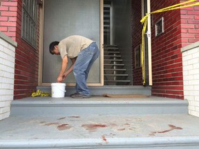 A man cleans blood off a porch following a stabbing in the 1700 block of College Avenue on May 26, 2015. (Dan Janisse/The Windsor Star)