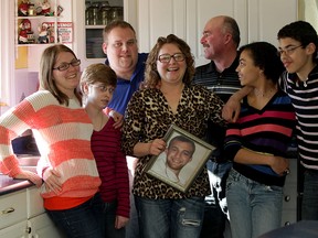 Joanne Sargent, centre, and husband Randy Dahl, behind, gather in the family kitchen with children Stephanie Sargent, left, Nettie Sargent-Dahl, Travis Sargent, Destiny Sargent-Dahl and Trenton Sargent-Dahl, right.  Joanne Sargent is holding a portrait of her late son, Alain, who died following a car accident. (NICK BRANCACCIO/The Windsor Star)