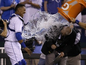 Kansas City Royals catcher Salvador Perez, left, dodges the water cooler as it lands on Fox announcer Joel Goldberg, right, following a baseball game against the Detroit Tigers at Kauffman Stadium in Kansas City, Mo., Friday, May 1, 2015. The Royals defeated the Tigers 4-1. (AP Photo/Orlin Wagner)