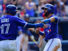 Toronto Blue Jays Jose Bautista (right) and Ryan Goins celebrate after both scoring on a Russell Martin single during sixth inning American League baseball action against the Los Angeles Angels in Toronto, Monday, May 18, 2015. THE CANADIAN PRESS/Frank Gunn