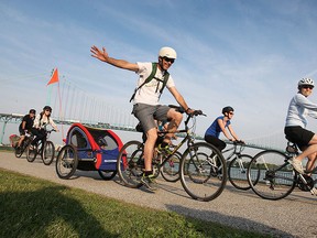 Local cyclists participate in the bike-to-work day on Friday, May 29, 2015, in Windsor, ON. John Fleming gives a wave as he towed his son Jimmy, 3, along.  (DAN JANISSE/The Windsor Star)
