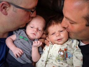 Brothers, Darryl Benjamin, left, and Chuck Benjamin, right,  kiss their sons Robert and Francis in Windsor, Ontario on May 27, 2015.  (JASON KRYK/The Windsor Star)