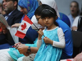 Sama Abdulla waves a flag as she joins other new Canadians taken the oath of citizenship at a special service at Catholic Central in Windsor on Friday, May 8, 2015. Thirty eight new Canadians were sworn in during the service. (TYLER BROWNBRIDGE/The Windsor Star)