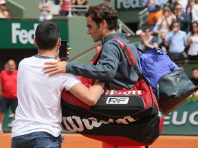 A boy who climbed down from the stands takes a selfie with Switzerland's Roger Federer in the first round match of the French Open tennis tournament against Colombia's Alejandro Falla at the Roland Garros stadium, in Paris, France, Sunday, May 24, 2015. (AP Photo/David Vincent)