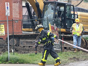 A firefighter stretches a hose at the scene of a gas leak in the 1500 block of Ouellette Ave. on Friday, May 15, 2015, in Windsor, ON. A main gas line was hit by a heavy machinery operator who was demolishing a building in the area. (DAN JANISSE/The Windsor Star)