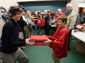 Keeghan Rorie, 17,  a player with the Ontario Minor Hockey Association, left, and  Spencer Martin, 12,  Windsor Minor Hockey Association help a large group of volunteers to unload hockey equipment that will be donated to underprivileged hockey players.  The "Let's Learn Hockey program" will be held at South Windsor Arena this weekend.   The novice hockey players will be able to keep the equipment provided by the Minor Hockey Foundation of Ontario.   Volunteers coaches from across Ontario are participating in the event. (JASON KRYK/The Windsor Star)
