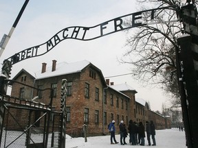 Tourists pause near the main entrance and a replica of the inscription "Arbeit Macht Frei" (Work Sets You Free) over the entrance to the former Nazi death camp Auschwitz-Birkenau, in Oswiecim, southern Poland. (Associated Press files)