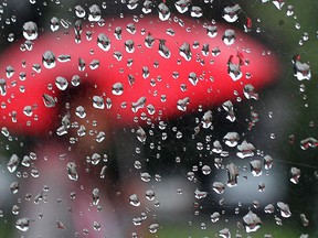 A pedestrian is reflected in a mirror in Windsor,  during a rainy day on May 31, 2015. (DAN JANISSE/THE WINDSOR STAR)