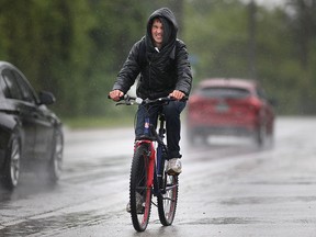 A cyclist makes his way down Malden Rd. in the pouring rain, Sunday, May 31, 2015.  (DAX MELMER/The Windsor Star)