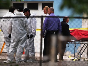 Windsor police forensics team, left, and lead investigators continue their "apparent homicide" investigation at rear of 536 Brant Street as body removal services, right, takes away the body of a man found dead Wednesday June 4, 2015.