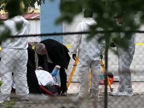 Windsor Police forensics team, left, and lead investigators continue their "apparent homicide" investigation at rear of 536 Brant Street as body removal services, right, takes away the body of a man found dead Wednesday June 4, 2015. (NICK BRANCACCIO/The Windsor Star)