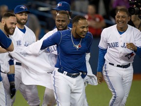 Toronto Blue Jays DH Edwin Enacarnacion, centre, gets his jersey ripped off after hitting a walk off two run home run to defeat the Miami Marlins during ninth inning interleague baseball action in Toronto on Tuesday, June 9, 2015. THE CANADIAN PRESS/Nathan Denette