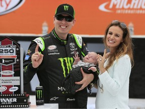 Kyle Busch, left, poses with his wife Samantha and 1-month-old Brexton Locke in the Winner's Circle after winning the NASCAR Xfinity series auto race at Michigan International Speedway, Saturday, June 13, 2015, in Brooklyn, Mich. (AP Photo/Carlos Osorio)