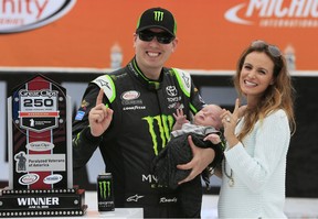 Kyle Busch, left, poses with his wife Samantha and 1-month-old Brexton Locke in the Winner's Circle after winning the NASCAR Xfinity series auto race at Michigan International Speedway, Saturday, June 13, 2015, in Brooklyn, Mich. (AP Photo/Carlos Osorio)