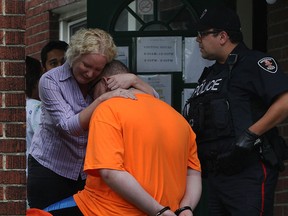 A woman, left, comforts a deaf man who was handcuffed following a stabbing at 1016 Pelissier Street Monday June 15, 2015. The male stabbing victim was taken to hospital by Essex-Windsor EMS paramedics.  Windsor police cruisers arrived and officers interviewed several witnesses at the multi-unit, two-storey complex.  Before the suspect was taken away in WPD prisoner transport vehicle, he was read his rights by police, with the woman using sign language to communicate. (NICK BRANCACCIO/The Windsor Star)