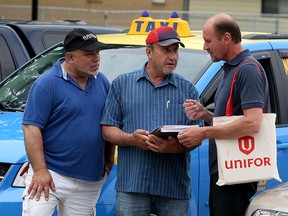 Unifor Local 195 Recording Secretary Mohamad Farhat, left,  Unit Chair Haidar Aouli and 1st Vice President John Toth discuss cab fare increase that would still leave Windsor taxi rates the lowest in the province, according to statistics supplied by Unifor Wednesday June 17,2015. (NICK BRANCACCIO/The Windsor Star).