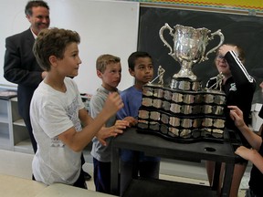 St. William Catholic School principal Joe Bachetti, top left, and student Tyler Tullio, left, display the Memorial Cup to the grade 7 class in Emeryville Monday. Tullio is the son of Rocco Tullio, the owner of the Memorial Cup champion Oshawa Generals. Also in the photo are classmates Spencer Tremblett, from left, Marcus Huggins, Alexa Burks, Natalie O’Brien, Julia Rogers and Serena Delicata. (NICK BRANCACCIO/The Windsor Star).