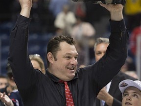Oshawa Generals head coach D.J. Smith raises the Memorial Cup trophy after they won the tournament 2-1 in overtime against the Kelowna Rockets Sunday, May 31, 2015 at the Memorial Cup final in Quebec City. THE CANADIAN PRESS/Jacques Boissinot
