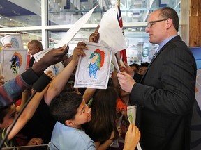The Ontario government announced a $2.5 million commitment to the City of Windsor on Monday, June 15, 2015, to help finance the 2016 World Swimming Championships at the Windsor International Aquatic Centre. Michael Coteau, Ontario Minister of Tourism, Culture and Sport was in Windsor to announce the funding. Mayor Drew Dilkens is mobbed by students from Immaculate Conception school who drew pictures of the game's mascot. (DAN JANISSE/The Windsor Star)