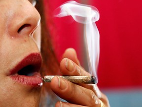 A woman smokes pot in her home on the first day of legal possession of marijuana for recreational purposes, Thursday, Feb. 26, 2015, in Washington. Scientific studies increasingly suggest marijuana is not the risk-free high that teens -- and sometimes their parents -- think it is, researchers say. THE CANADIAN PRESS/AP/Alex Brandon
