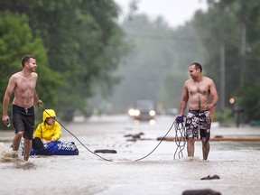 Andrew Roberts, left, and Kurt Makey pull Rebecca Wright in a dingy down a flooded Coterie Park Road outside Wheatley after 3-4 metre high waves and rain flooded the street, Saturday, June 27, 2015.  (DAX MELMER/The Windsor Star)