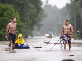 Andrew Roberts, left, and Kurt Makey pull Rebecca Wright in a dingy down a flooded Coterie Park outside Wheatley after 3-4 metre high waves and rain flooded the street, Saturday, June 27, 2015.