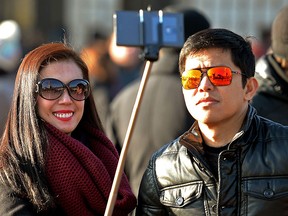 FILE - In this Jan. 23, 2015 file photo, tourists use a 'selfie stick' in London. (AP Photo/PA, John Stillwell)