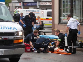 EMS Paramedics tend to a young man with apparent stab wounds on Wyandotte St. W. at Dougall Ave., Sunday, June 14, 2015.  (DAX MELMER/The Windsor Star)