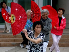 Local members of the Chinese community perform the ancient Chinese martial art of T'ai Chi with fans in front of the Ontario Court of Justice on Chatham Street Tuesday July 8, 2015. About a dozen members made dance movements to music during their evening street session. (NICK BRANCACCIO/The Windsor Star).