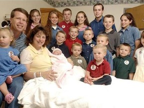 FILE - In this Aug. 2, 2007 file photo, Michelle Duggar, left, is surrounded by her children and husband Jim Bob, second from left, after the birth of her 17th child in Rogers, Ark. TLC is officially cancelling "19 Kids and Counting." The hit reality show "will no longer appear on the air," the network told The Associated Press on Thursday, July 15, 2015. The show had been in limbo since May after revelations that 27-year-old Josh Duggar molested five children including four of his sisters. (AP Photo/ Beth Hall, File)