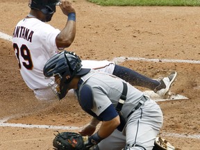 Minnesota Twins'  Danny Santana (39) scores from third base on a sacrifice fly to center as Detroit Tigers catcher Alex Avila, bottom, gets the late throw during the fourth inning of a baseball game in Minneapolis, Sunday, July 12, 2015. The Twins won 7-1. (AP Photo/Ann Heisenfelt)