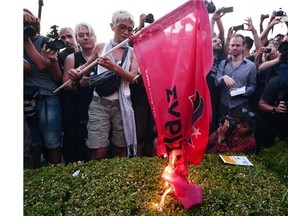 A woman burns the flag of the ruling party Syriza in front of the Greek parliament in Athens, during an anti-EU protest on July 13 , 2015.