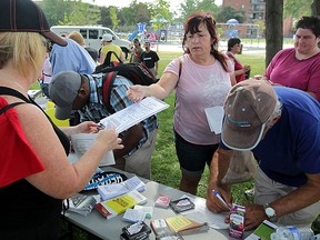 Area resident Roxanne Denault, centre, receives a Hepatitis C questionnaire from RN Beth McLellan, left, during a World Hepatitis Day BBQ at Wigle Park Tuesday July 28, 2015. Multiple stations around Wigle Park were set up by Windsor Essex Community Health Centre Hepatitis C Treatment and Support Team. Visitors were given a World Hepatitis Day Pass to use as they made stops at each display.  Hot dogs, water, chips and fresh vegetables were available. (NICK BRANCACCIO/The Windsor Star)
