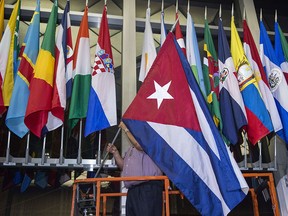 Workers at the U.S. Department of State add the Cuban flag at to the display of flags inside the main entrance at 202 "C" Street at 4 a.m. local time (0800 GMT) in Washington, D.C. on July 20, 2015. The United States and Cuba formally resumed diplomatic relations on July 20, as the Cuban flag was raised at the U.S. State Department in a historic gesture toward ending decades of hostility between the Cold War foes.      AFP PHOTO / Paul J. Richards