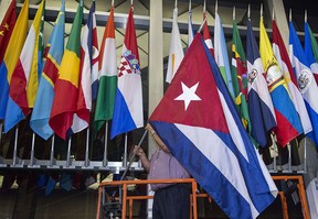 Workers at the U.S. Department of State add the Cuban flag at to the display of flags inside the main entrance at 202 "C" Street at 4 a.m. local time (0800 GMT) in Washington, D.C. on July 20, 2015. The United States and Cuba formally resumed diplomatic relations on July 20, as the Cuban flag was raised at the U.S. State Department in a historic gesture toward ending decades of hostility between the Cold War foes.      AFP PHOTO / Paul J. Richards