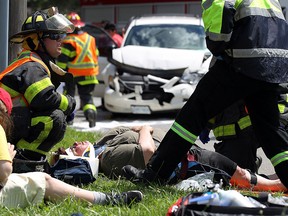 Paramedics and firefighters tend to several victims at the scene of a two car accident at the corner of St. Luke Road and Richmond Street in Windsor on Friday, July 31, 2015. Numerous people were injured and had to be transported to hospital. Police are investigating the cause of the accident that let one car upside down. (TYLER BROWNBRIDGE/The Windsor Star)