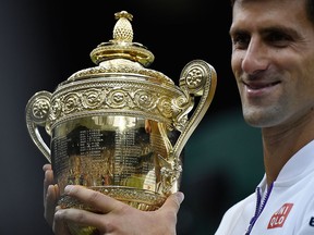 Novak Djokovic of Serbia holds the trophy after winning the men's singles final against Roger Federer of Switzerland at the All England Lawn Tennis Championships in Wimbledon, London, Sunday July 12, 2015. Djokovic won the match 7-6, 6-7, 6-4, 6-3.  (Toby Melville/Pool Photo via AP)