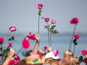 People wait to toss pink roses into Lake St. Clair during the rose ceremony at the International Dragon Boat Festival for the Cure at Tecumseh Waterfront Park, Sunday, July 19, 2015.  (DAX MELMER/The Windsor Star)