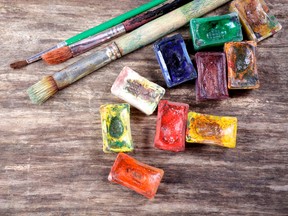 Watercolor paints and brushes, painting tools on an old wooden board. Photo by fotolia.com.
