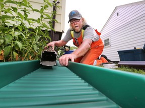 Keith Devlin, of the city's field engineering department, disconnects a downspout at a home on Josephine Avenue in Windsor on July 3, 2015. He then installs a piece of eavestrough to send the water away from the home, which helps avoid flooding. (DAN JANISSE/The Windsor Star)