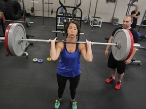 Doris Hellenbart, 67, pauses with the weight on her shoulders, during clean and jerk reps with strength coach Erik Brinkman, right, at Body X recently. (NICK BRANCACCIO / The Windsor Star)