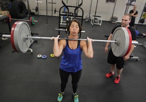 Doris Hellenbart, 67, pauses with the weight on her shoulders, during clean and jerk reps with strength coach Erik Brinkman, right, at Body X recently. (NICK BRANCACCIO / The Windsor Star)