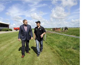 NDP Leader Tom Mulcair, left, speaks with dairy farmer Pedro Slits at the Slits Dairy Farm in Brunner, Ont., on Wednesday, July 22, 2015. Mulcair is on his Ontario Tour for Change which is highlighting the party's plan to support opportunities for farmers and to help ensure healthy and affordable food for middle-class families. (Postmedia News files)