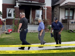 Windsor Police fire investigators Constable Greg Meloche, left, and Constable Mike Akpata, right, assist coroner Dr. Marven Oxley at 1407 Aubin Road, Tuesday August 12, 2015.  Windsor Police have not released the name or gender of the deceased following a fire overnight.  (NICK BRANCACCIO/The Windsor Star)
