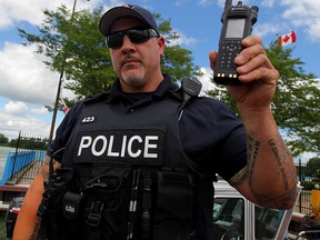 Constable Shannon Tennant, Windsor Police marine unit, holds the new radio in his left hand at Lakeview Park Marina. (NICK BRANCACCIO/The Windsor Star)