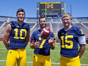 Michigan quarterbacks Zach Gentry (10), Shane Morris (7), and Jake Rudock (15) pose for a photo  in Michigan Stadium during the NCAA college football team's annual media day in Ann Arbor, Mich., Thursday, Aug. 6, 2015. (AP Photo/Tony Ding)