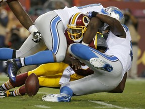 Washington Redskins quarterback Robert Griffin III fumbles the ball as he's sacked by Detroit Lions defensive end Tyrunn Walker, top, and defensive end Ezekiel Ansah, right, during the first half of an NFL preseason football game, Thursday, Aug. 20, 2015, in Landover, Md. (AP Photo/Alex Brandon)
