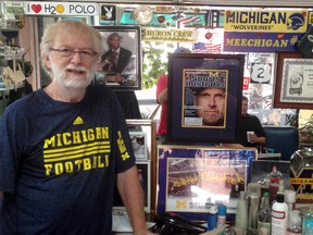 Barber Bill Stolberg stands next to his Michigan memorabilia in his shop in Ann Arbor, Mich. (AP Photo/Noah Trister)