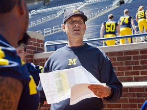 Michigan head coach Jim Harbaugh coordinates his players to lineup in the Michigan Stadium stands for a team photo, during the NCAA college football team's annual media day in Ann Arbor, Mich., Thursday, Aug. 6, 2015. (AP Photo/Tony Ding)