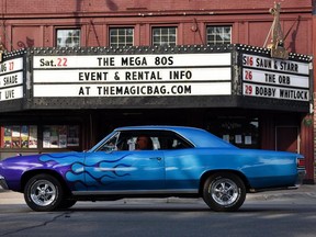 A classic car with blue flames cruises past The Magic Bag on Woodward Avenue during the Woodward Dream Cruise, Friday, Aug. 14, 2015, in Royal Oak, Mich. (Tanya Moutzalias/The Ann Arbor News-MLive.com Detroit via AP)